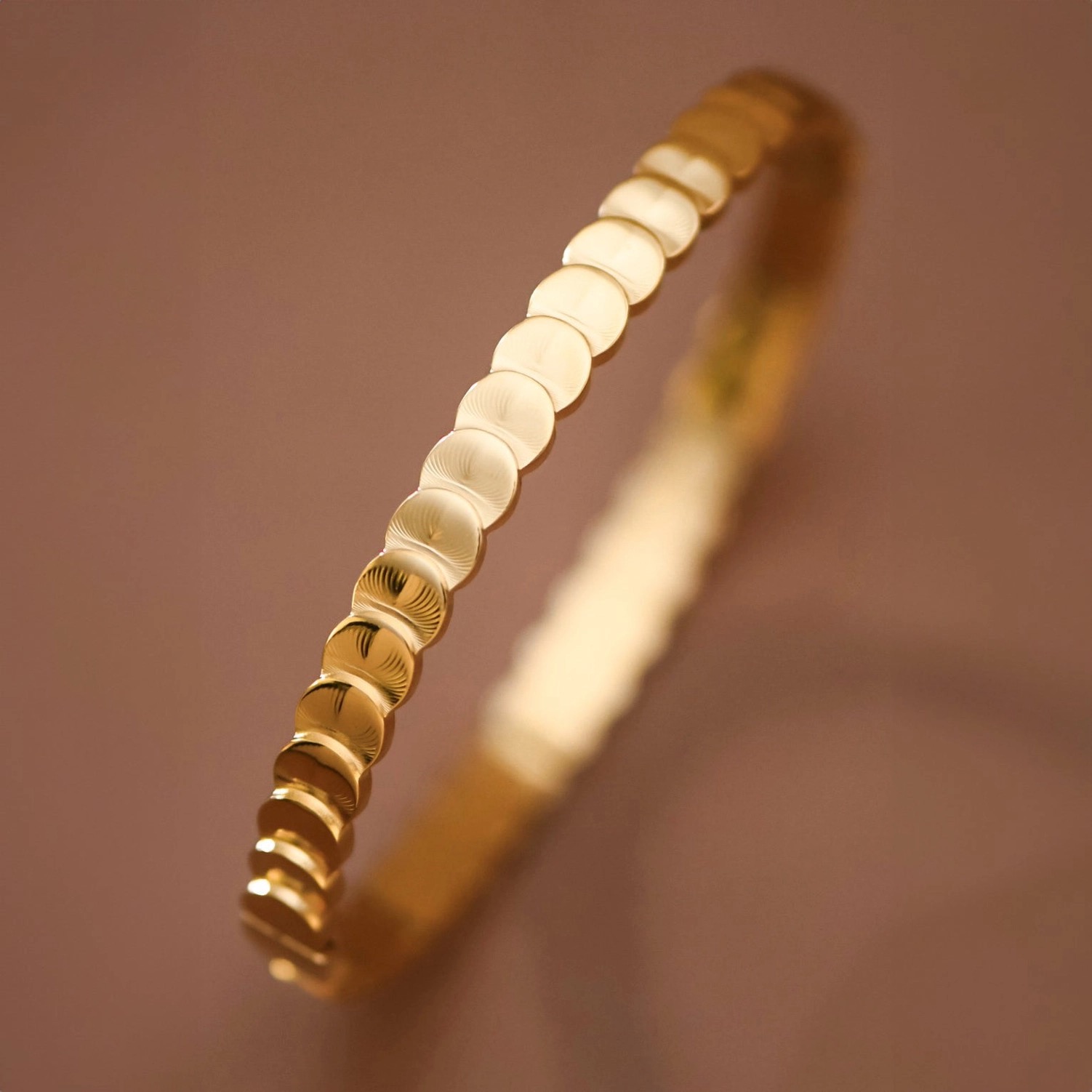 Close detail of a beaded gold bangle in warm light